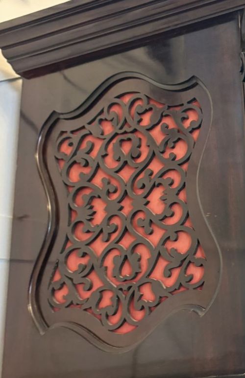 fig 6. A tall carved dark mahogany longcase clock featuring an ornate pediment, brass dial with moon phase indicator, and a glazed door displaying nine tubular chimes.