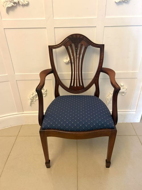 fig 3. A set of twelve mahogany shield back dining chairs featuring intricate carved splats and patterned blue upholstered seats, arranged in three rows.