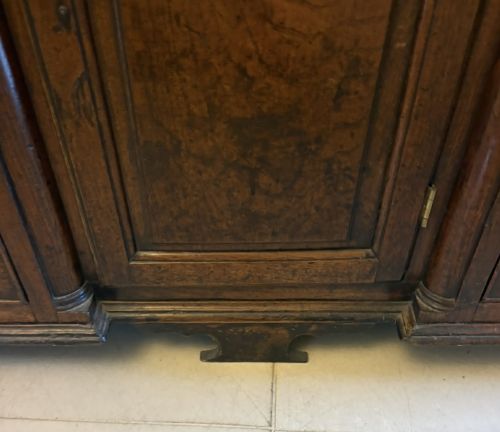 fig 3. A dark oak Georgian Lancashire dresser with a scalloped open plate rack, central cupboard section, and base containing multiple drawers with brass handles.