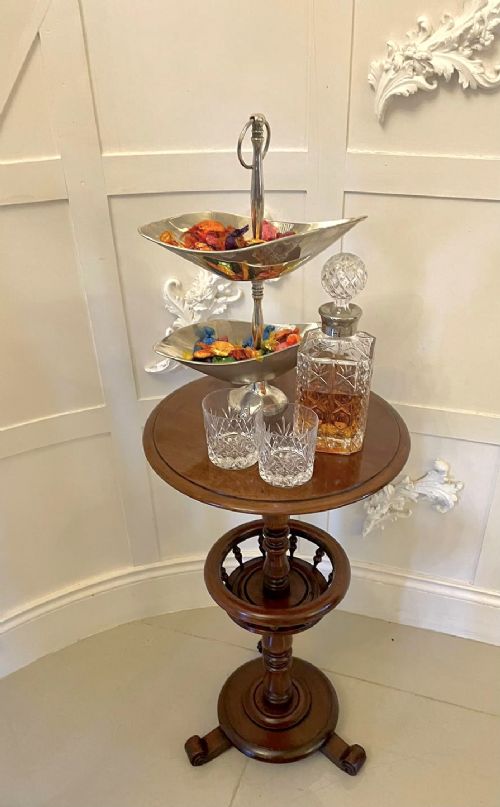 An antique Victorian circular mahogany lamp table featuring a central turned stem with an integrated balustrade mid-tier gallery, resting on a tripod base with scroll feet. View IX