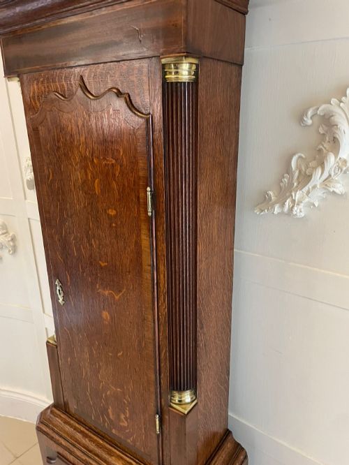 fig 2. An antique George III oak longcase clock featuring a swan-neck pediment, brass fittings, and a painted arch dial with Roman numerals.