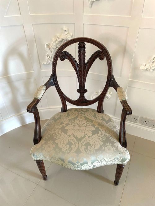 fig 1. A pair of carved mahogany open armchairs featuring oval backs with carved splats, padded armrests, and pale green patterned fabric seats on fluted front legs.