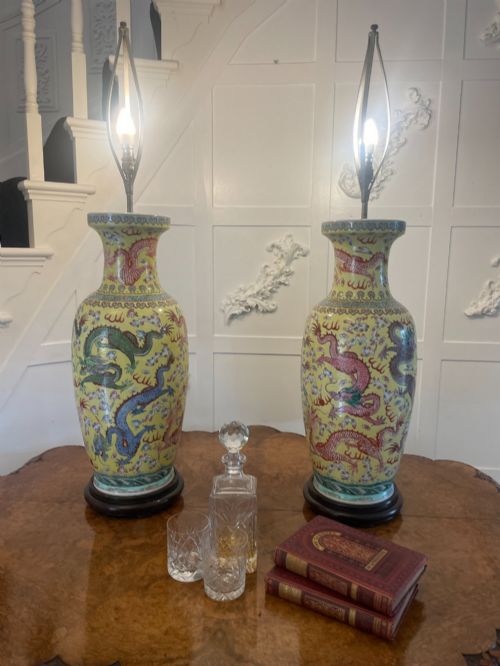 fig 1. A pair of large 19th-century Chinese porcelain vase lamps featuring hand-painted dragons on a yellow ground, set on dark wooden bases.