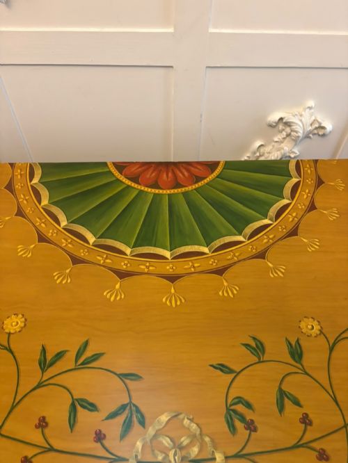 fig 7. A semicircular satinwood demi-lune cabinet featuring hand-painted neoclassical leaf swags, a central figural medallion, and short tapered feet.