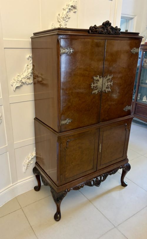 An antique burr walnut cocktail cabinet featuring decorative brass hardware, carved scroll cresting, two cupboard sections, and cabriole legs. View XIII