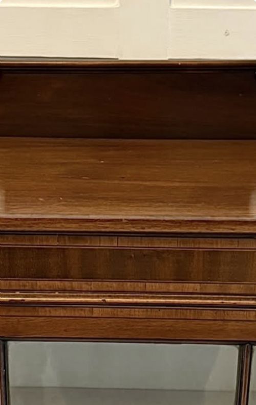fig 2. An Edwardian mahogany glazed display cabinet featuring geometric glazing bars, tapered legs, a raised pediment top, and a light-lined interior with three shelves.