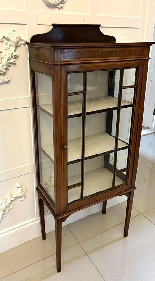 An Edwardian mahogany glazed display cabinet featuring geometric glazing bars, tapered legs, a raised pediment top, and a light-lined interior with three shelves. View VII