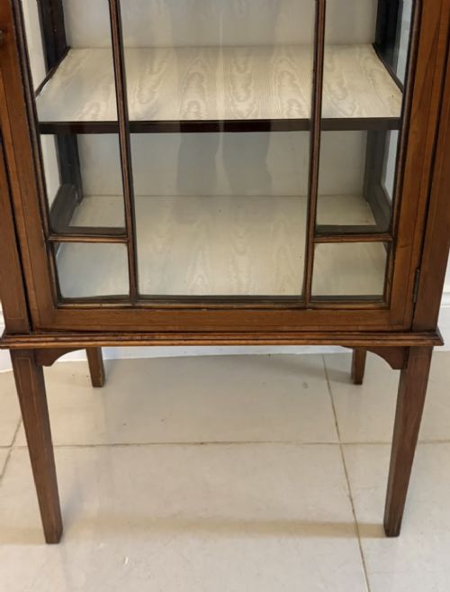 An Edwardian mahogany glazed display cabinet featuring geometric glazing bars, tapered legs, a raised pediment top, and a light-lined interior with three shelves. View X