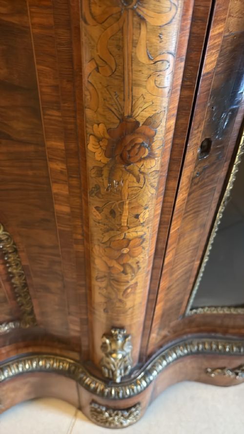 fig 3. A Victorian serpentine burr walnut credenza featuring detailed floral marquetry inlays, gilt-bronze mounts, a central panelled door, and two curved glazed side doors.