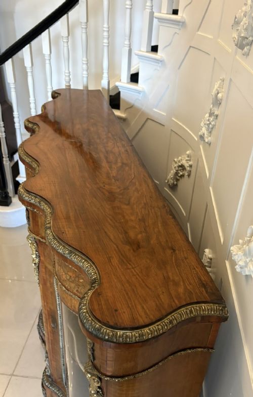 A Victorian serpentine burr walnut credenza featuring detailed floral marquetry inlays, gilt-bronze mounts, a central panelled door, and two curved glazed side doors. View X