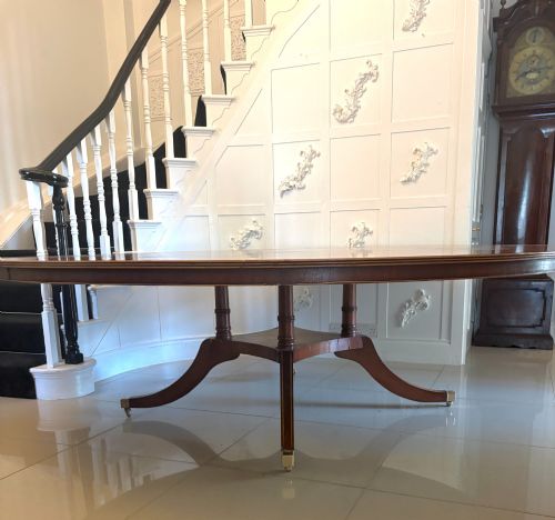 fig 2. A large circular mahogany dining table featuring a yew wood crossbanded border and a central pedestal base.
