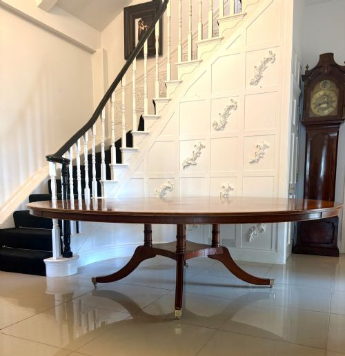 fig 3. A large circular mahogany dining table featuring a yew wood crossbanded border and a central pedestal base.