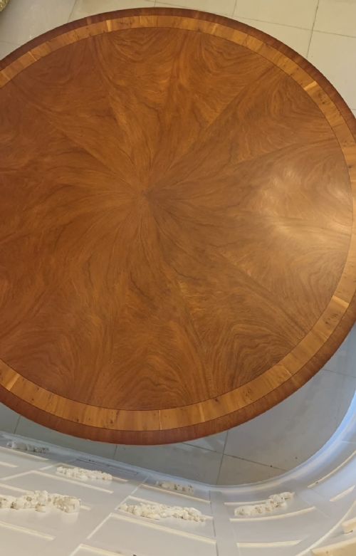 A large circular mahogany dining table featuring a yew wood crossbanded border and a central pedestal base. View XII
