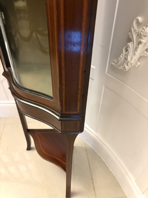 fig 2. An Edwardian mahogany corner display cabinet with a serpentine glazed door, line inlay decoration, shaped upper pediment, and slender tapered legs with a lower undertier.
