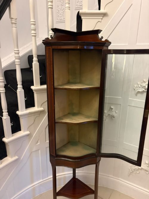 fig 3. An Edwardian mahogany corner display cabinet with a serpentine glazed door, line inlay decoration, shaped upper pediment, and slender tapered legs with a lower undertier.