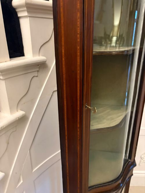 fig 6. An Edwardian mahogany corner display cabinet with a serpentine glazed door, line inlay decoration, shaped upper pediment, and slender tapered legs with a lower undertier.