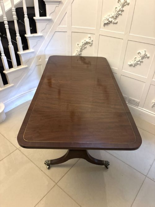 fig 4. A Regency mahogany sofa table featuring two drop leaves, two front drawers with round brass knobs, reeded splayed legs, and brass paw castors.