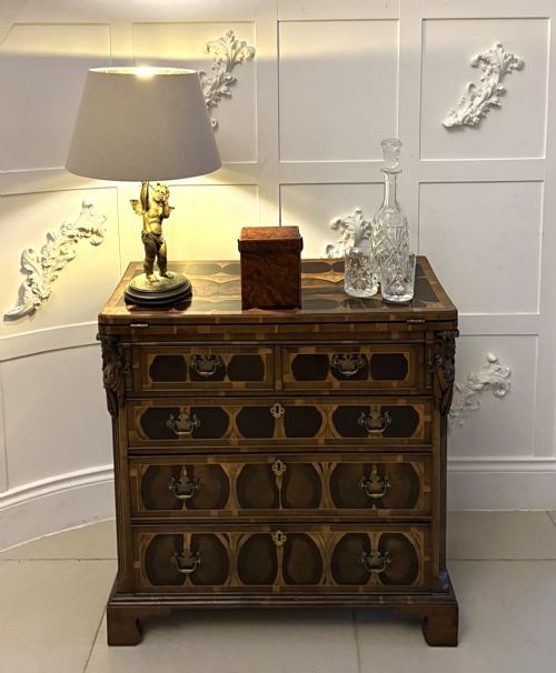 fig 4. A George I yew wood and laburnum oyster veneered bachelors chest of drawers with carved corner caryatids and brass drop handles.