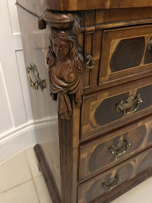 fig 5. A George I yew wood and laburnum oyster veneered bachelors chest of drawers with carved corner caryatids and brass drop handles.
