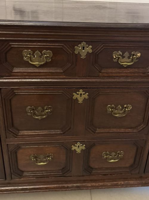 An antique dark oak Georgian dresser base featuring geometric panel drawers, brass handles, side cupboard doors, and a smooth wooden surface. View VIII