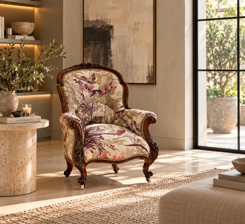 fig 1. An antique Victorian carved rosewood armchair featuring floral and bird pattern upholstery with cabriole legs on castors.