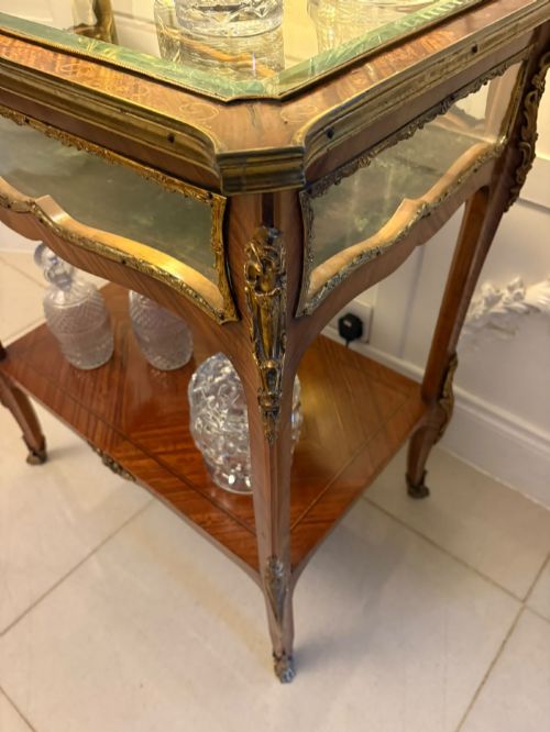 fig 1. An antique French Napoleon III satinwood bijouterie table featuring a glazed display top, curved cabriole legs with decorative brass mounts, and an undertier shelf.