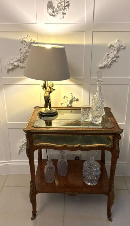 fig 3. An antique French Napoleon III satinwood bijouterie table featuring a glazed display top, curved cabriole legs with decorative brass mounts, and an undertier shelf.
