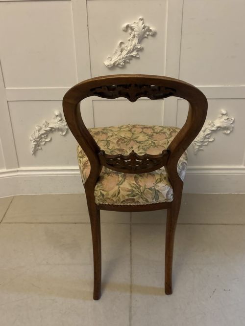 fig 1. A set of four Victorian carved walnut dining chairs featuring open balloon backs, carved crest details, cabriole front legs, and floral pattern upholstered seats.