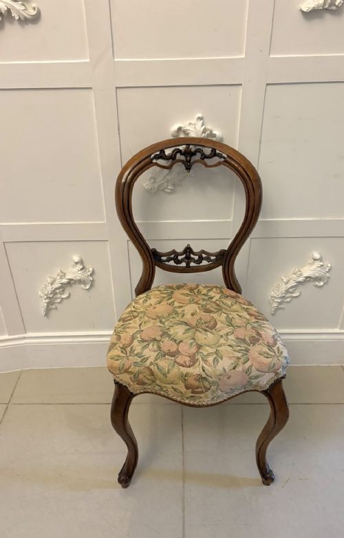 A set of four Victorian carved walnut dining chairs featuring open balloon backs, carved crest details, cabriole front legs, and floral pattern upholstered seats. View IX