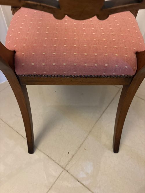 fig 4. An antique mahogany carver dining chair with sweeping armrests, a carved central roundel crest bar, and a pink patterned upholstered seat.