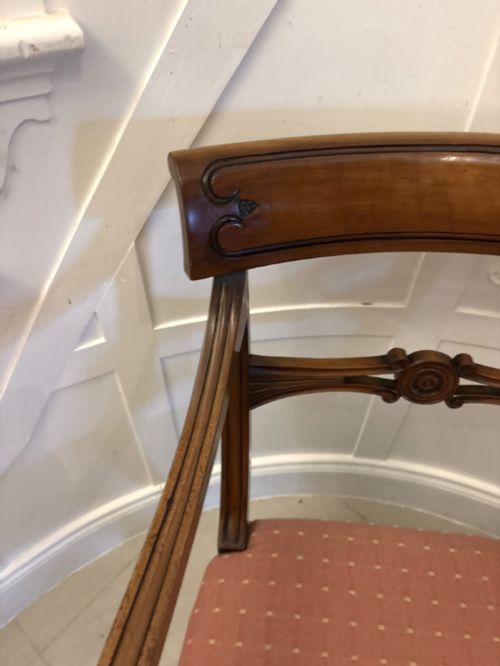 fig 5. An antique mahogany carver dining chair with sweeping armrests, a carved central roundel crest bar, and a pink patterned upholstered seat.