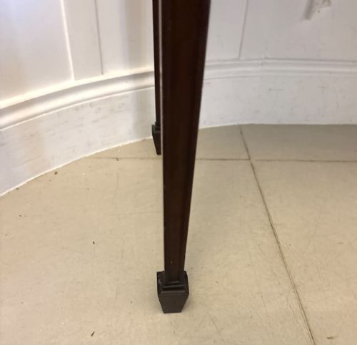 fig 3. An Edwardian mahogany console table featuring a serpentine front, carved central motif, brass handles, and square tapered legs.