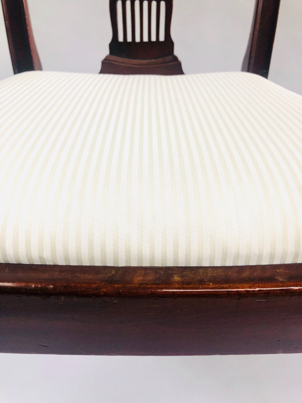 A set of four dark mahogany dining chairs featuring carved fan splats, cream upholstered seats, and tapered legs. View IX