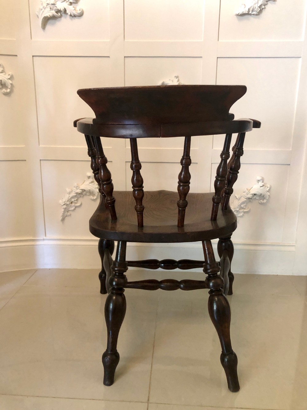 An antique dark oak captains desk chair featuring a curved crest rail, turned spindles, a contoured saddle seat, and sturdy turned legs. View III