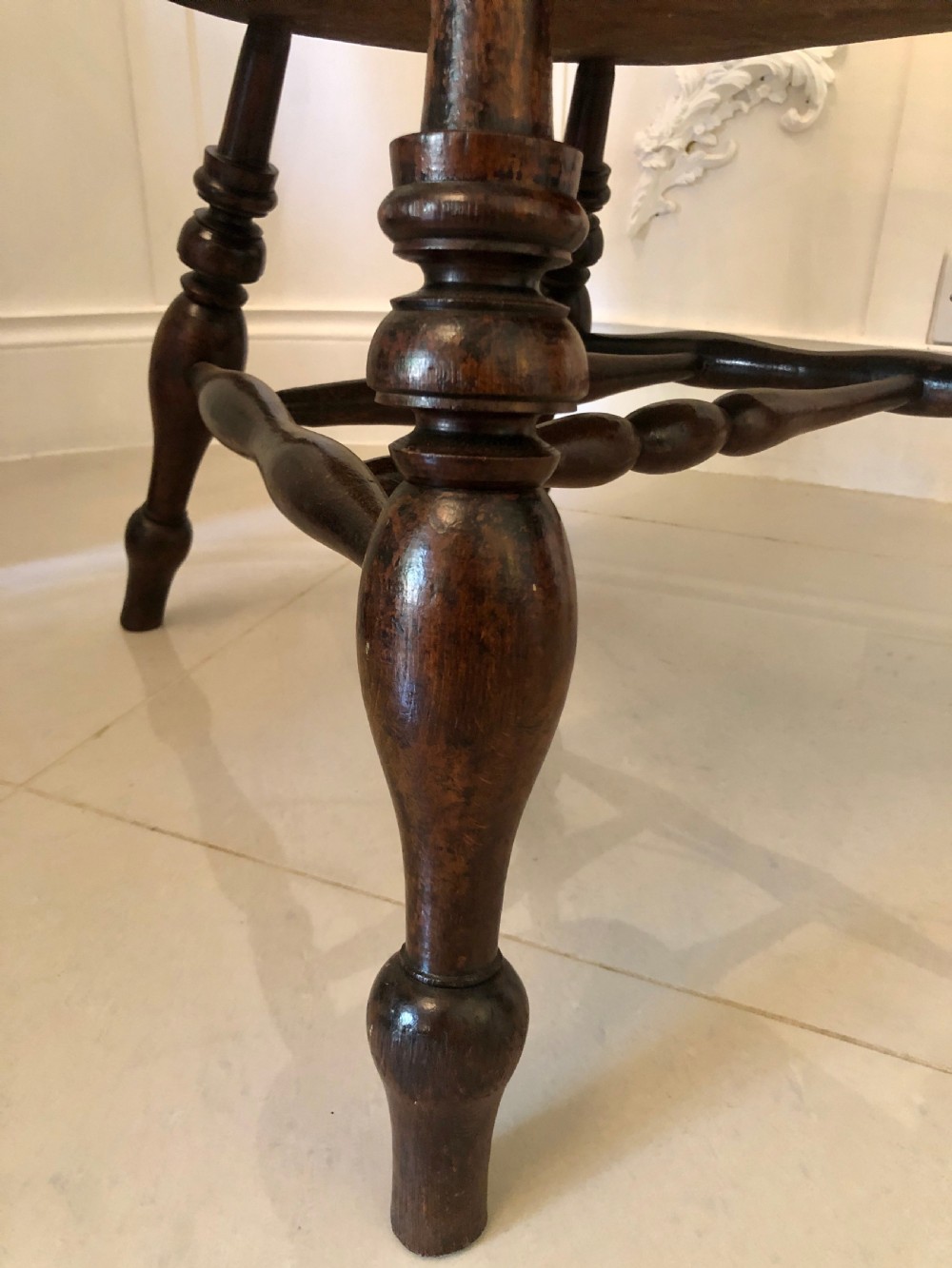 An antique dark oak captains desk chair featuring a curved crest rail, turned spindles, a contoured saddle seat, and sturdy turned legs. View V