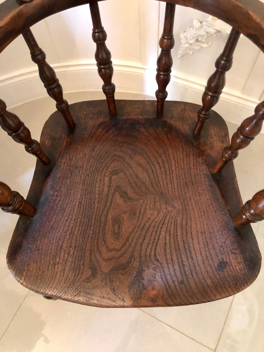 An antique dark oak captains desk chair featuring a curved crest rail, turned spindles, a contoured saddle seat, and sturdy turned legs. View VI
