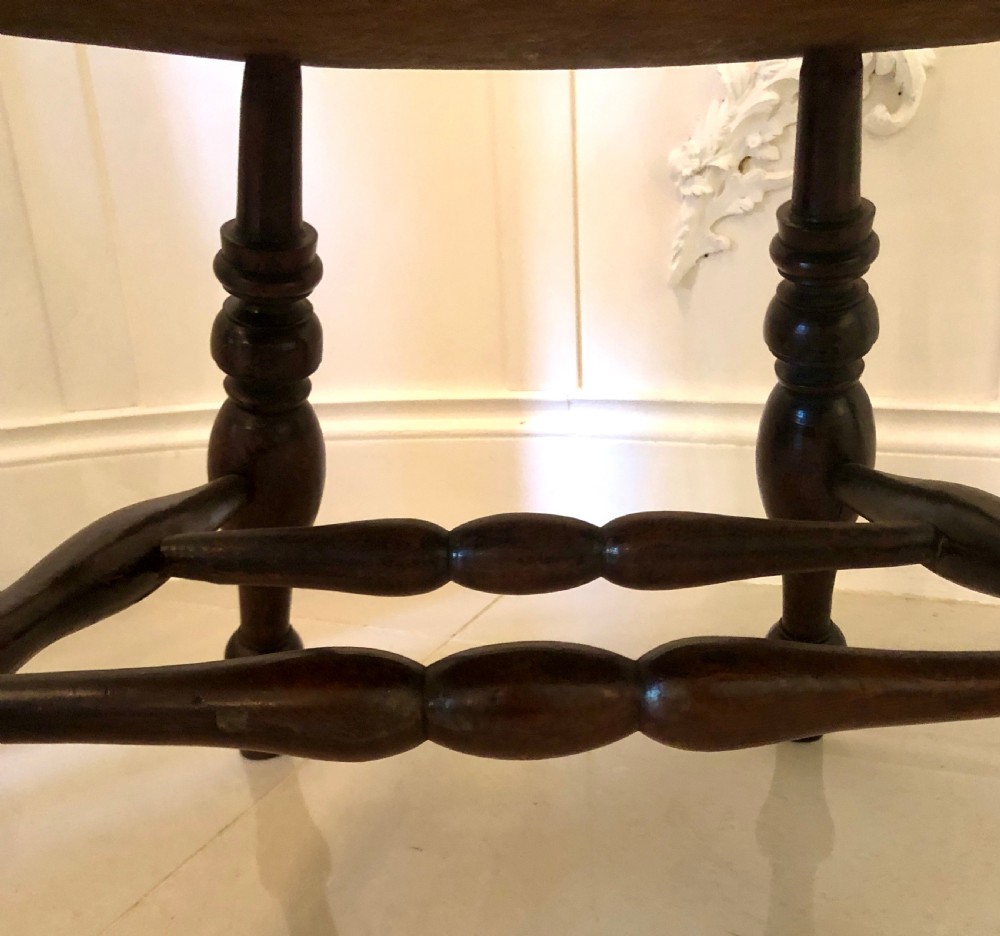 An antique dark oak captains desk chair featuring a curved crest rail, turned spindles, a contoured saddle seat, and sturdy turned legs. View VIII
