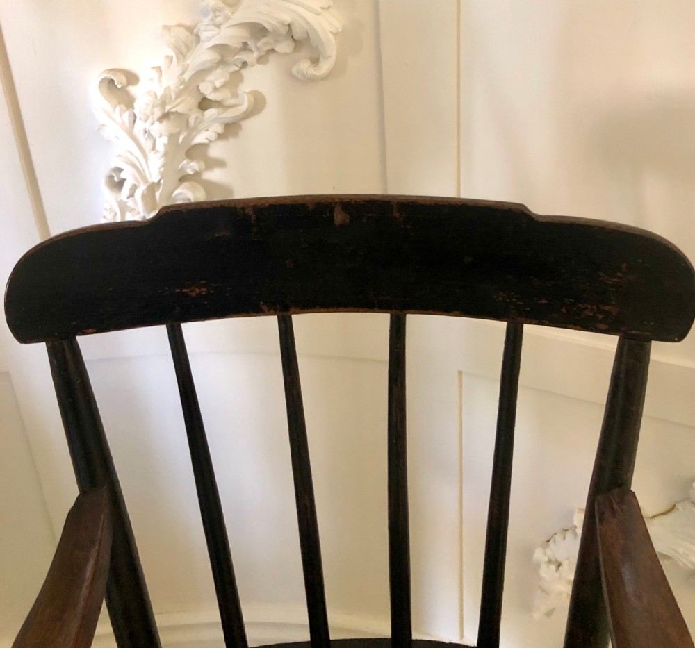 A dark-stained wooden antique child high chair featuring a vertical spindle backrest, armrests, splayed legs, and a built-in wooden footrest. View VII