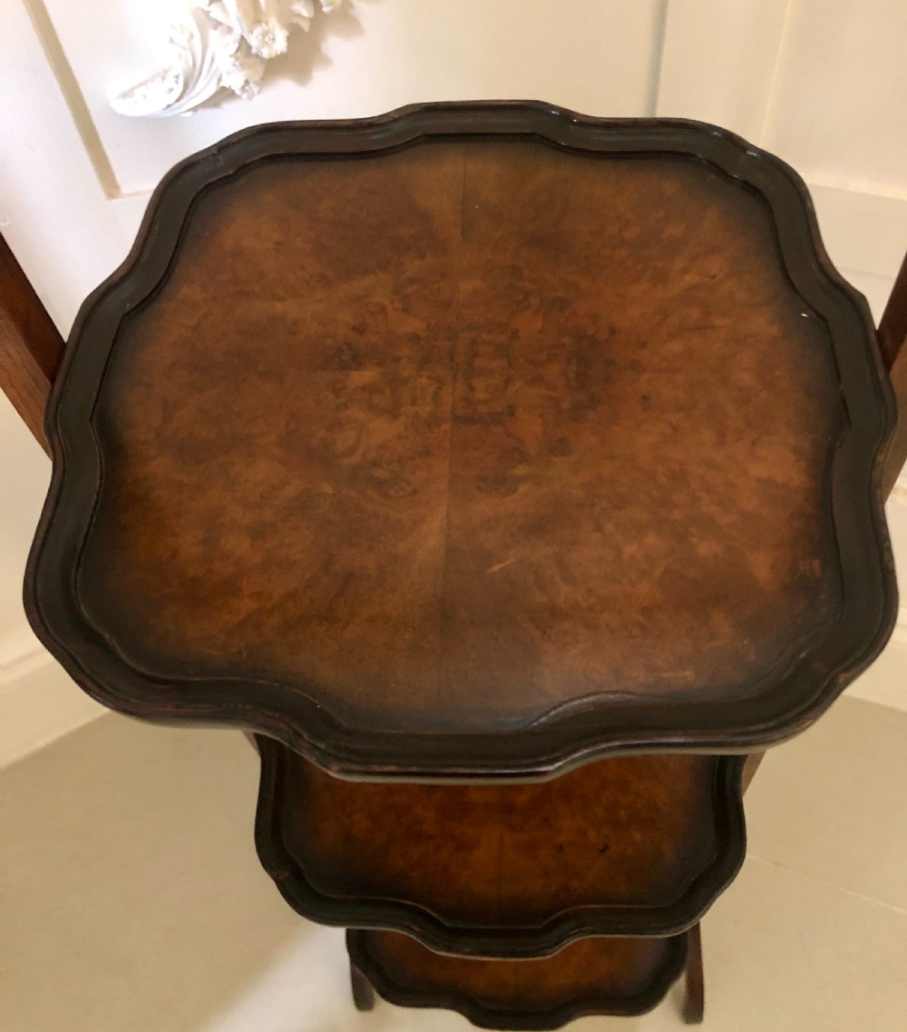 An antique three-tier walnut folding cake stand featuring shaped moulded trays, a curved top carrying handle, and straight wooden side supports. View VI
