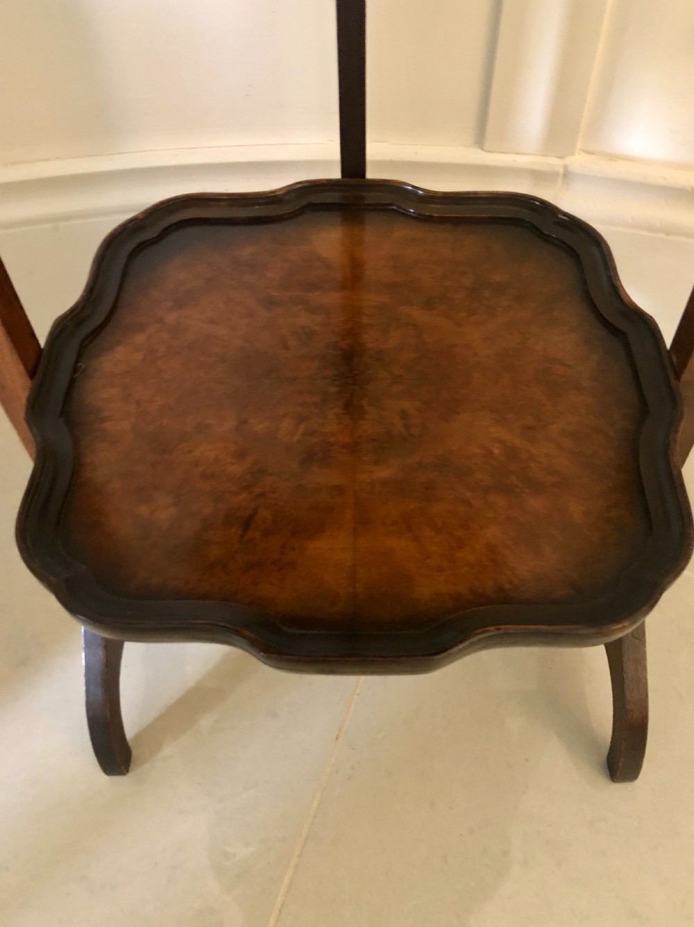 An antique three-tier walnut folding cake stand featuring shaped moulded trays, a curved top carrying handle, and straight wooden side supports. View VII