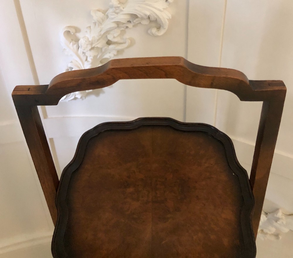 An antique three-tier walnut folding cake stand featuring shaped moulded trays, a curved top carrying handle, and straight wooden side supports. View XI