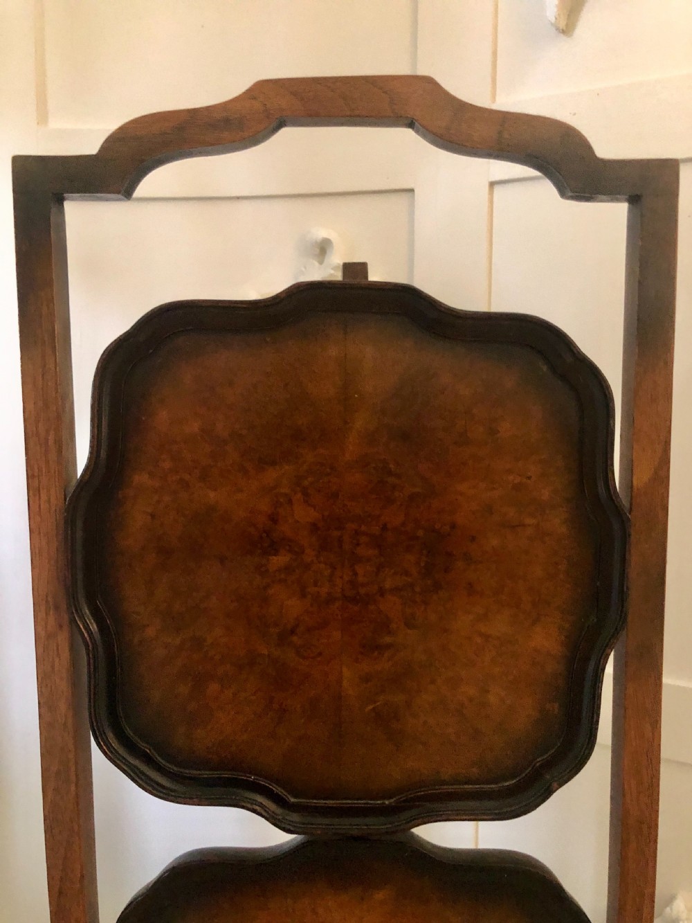 An antique three-tier walnut folding cake stand featuring shaped moulded trays, a curved top carrying handle, and straight wooden side supports. View XIV
