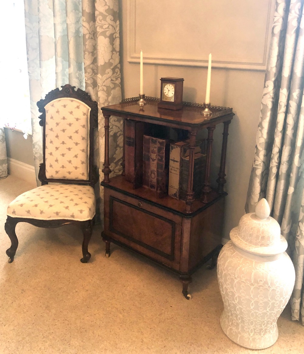 A Victorian carved rosewood ladies chair featuring a high upholstered backrest and seat with a grey bee pattern on cream fabric, raised on cabriole front legs with brass castors. View III