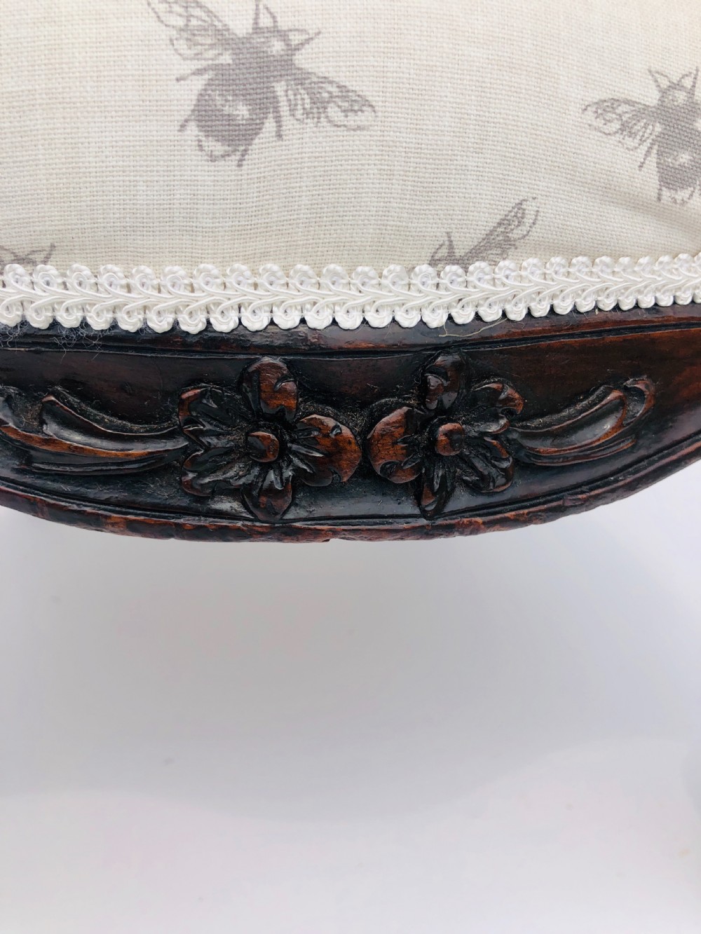A Victorian carved rosewood ladies chair featuring a high upholstered backrest and seat with a grey bee pattern on cream fabric, raised on cabriole front legs with brass castors. View IV