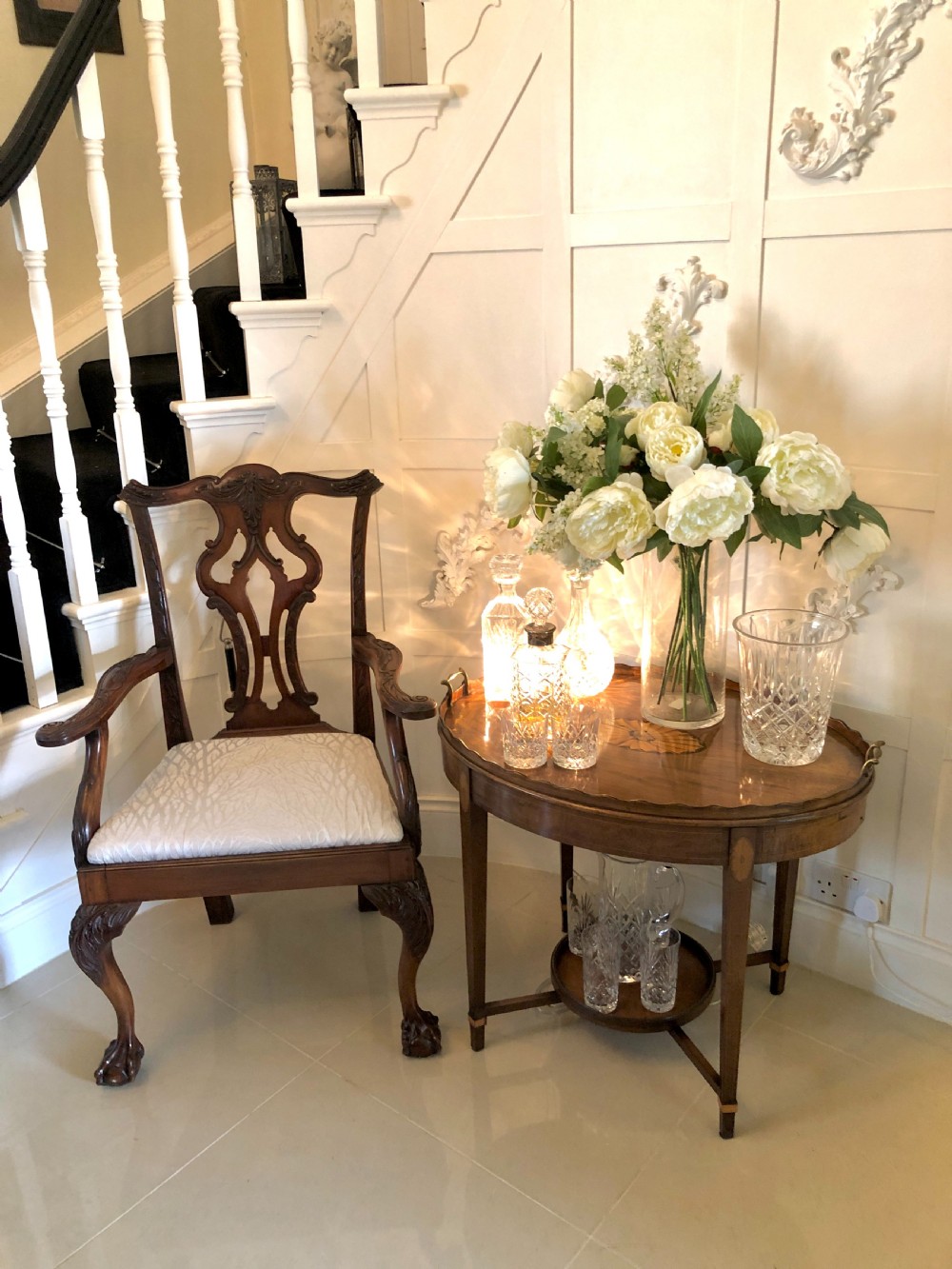 An Edwardian oval mahogany tray table with brass carrying handles, satinwood inlay, tapered legs, and a lower circular tier. View II