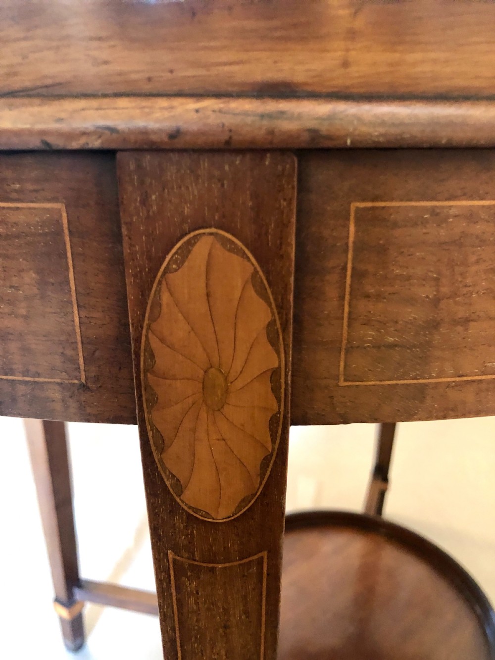 An Edwardian oval mahogany tray table with brass carrying handles, satinwood inlay, tapered legs, and a lower circular tier. View V