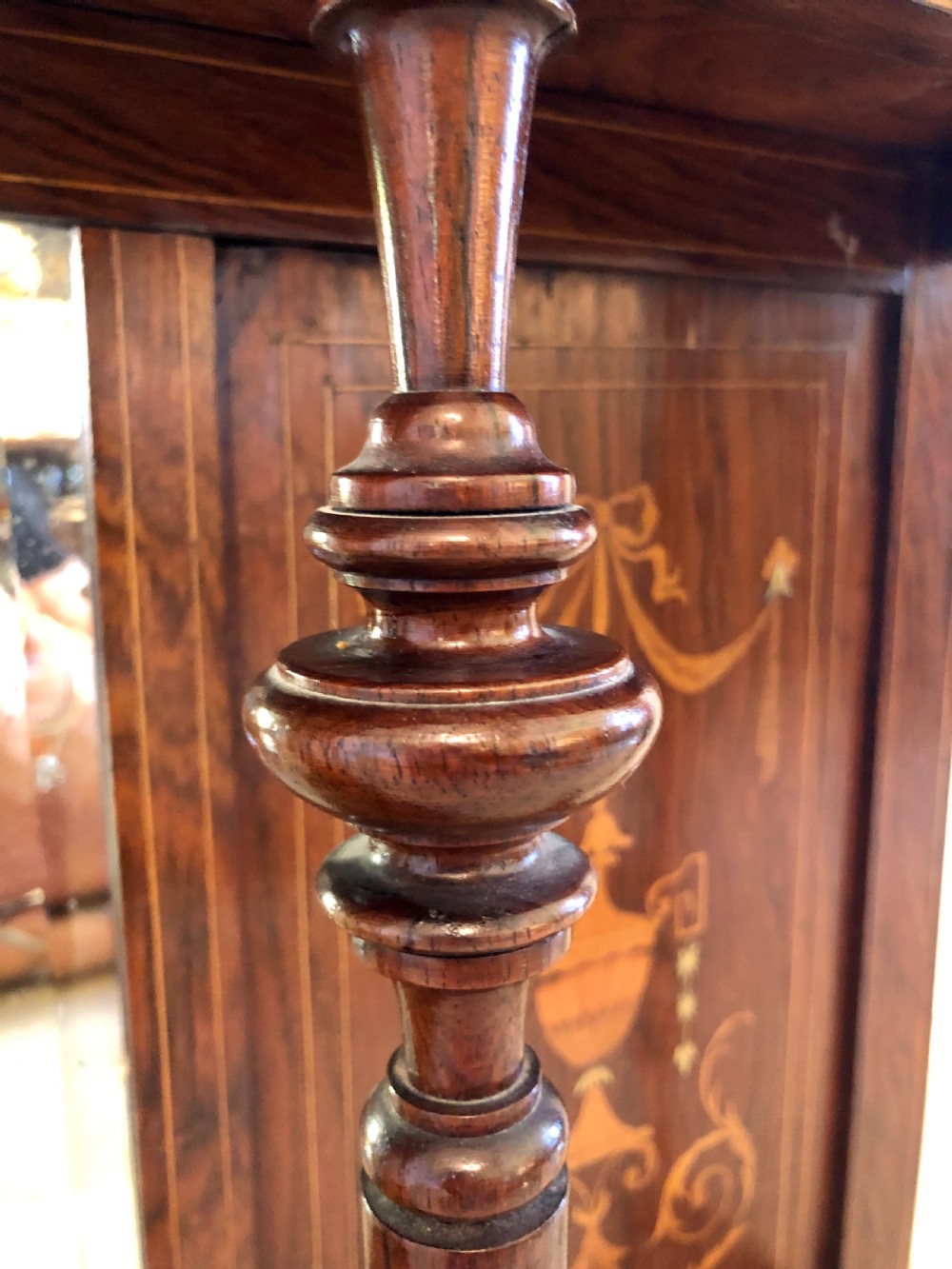 An Edwardian rosewood overmantel mirror featuring detailed bow and urn marquetry inlays, turned supporting columns, and a central rectangular glass plate. View VI