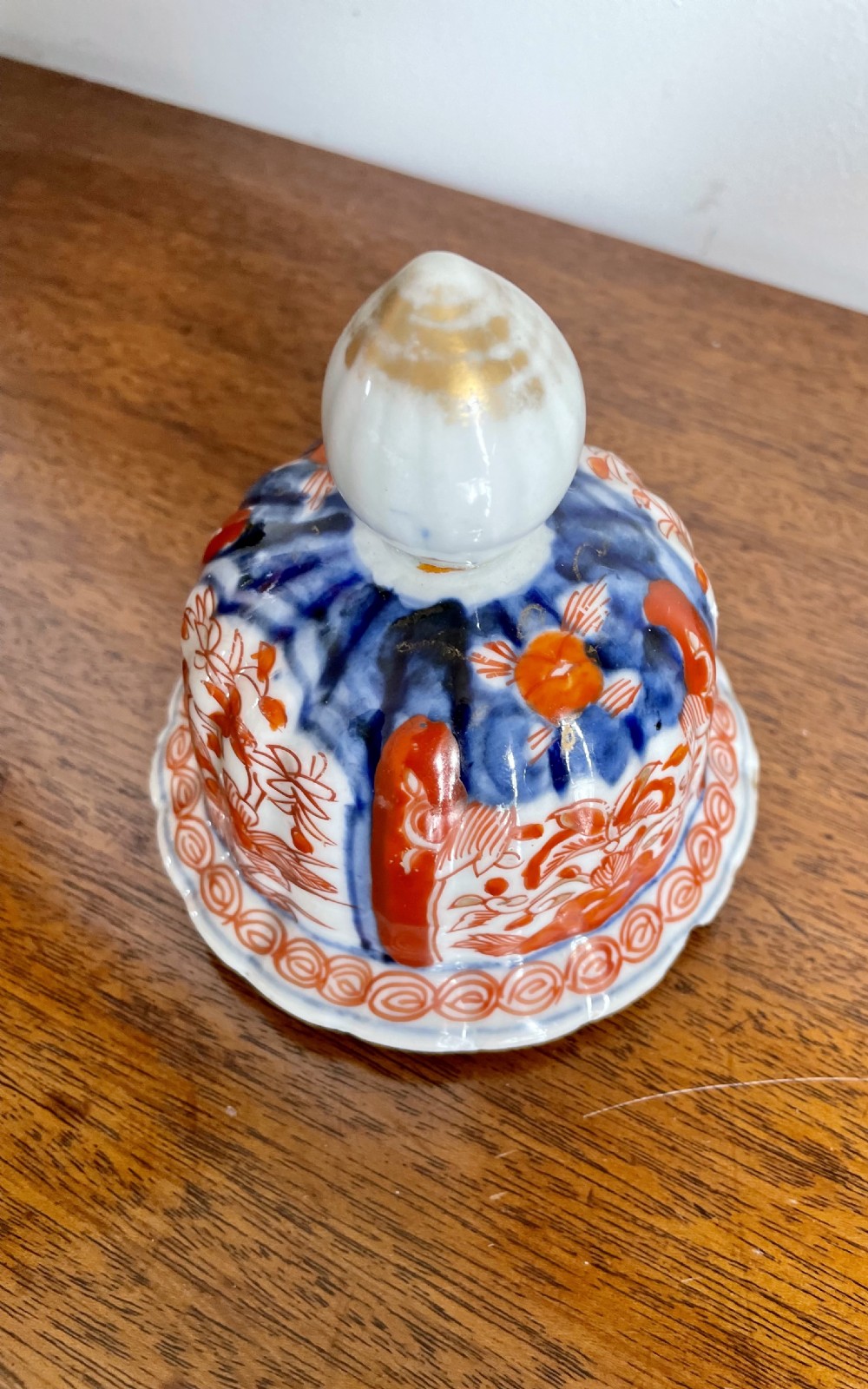 A fluted ceramic Imari vase with a matching lid, decorated in hand-painted floral patterns of iron-red and cobalt blue on a white background. View III