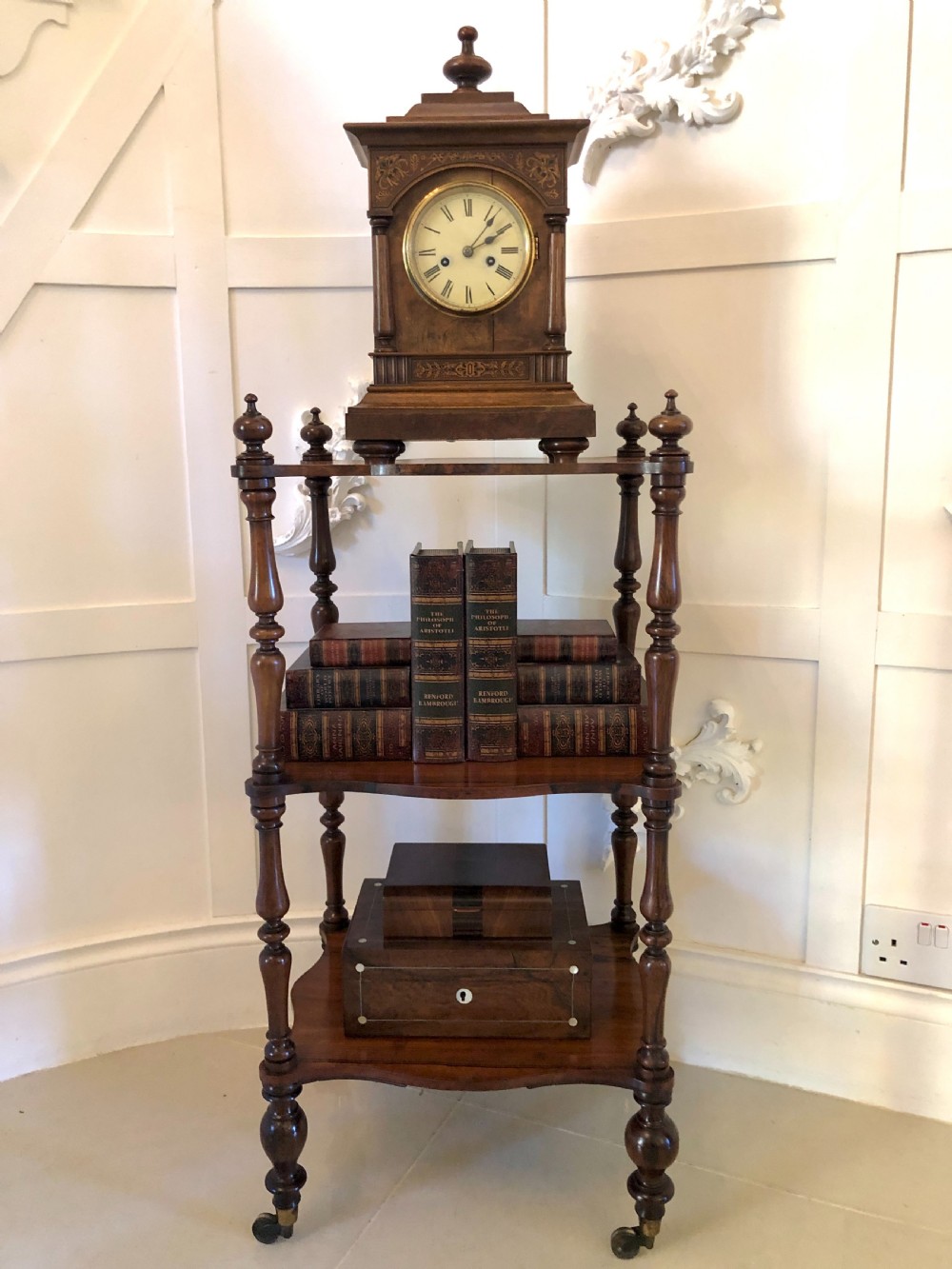 A three-tiered Victorian rosewood whatnot featuring serpentine shelf edges, turned corner supports, decorative finials, and brass castors. View II