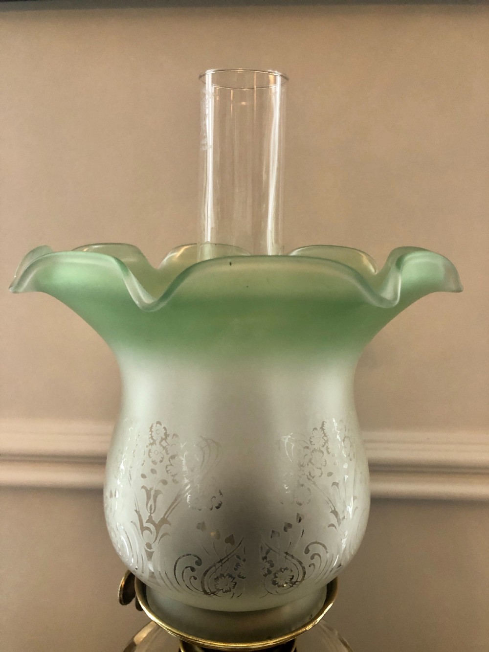A Victorian oil lamp featuring a weighted brass base, clear glass reservoir, etched glass shade with a green crimped rim, and a tall clear glass chimney. View II